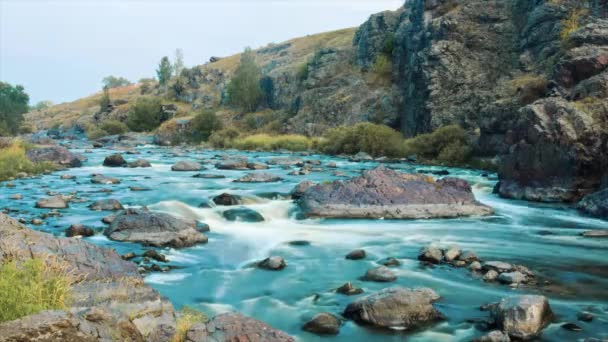 Beautiful річкової води, що протікає через камені та скелі на світанку. Відео. Течії річки через камені. Timelapse. Молода людина розслабляється на скелі — стокове відео