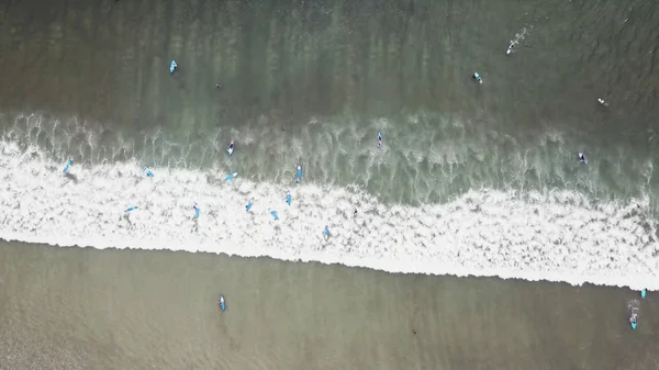 Eine Luftaufnahme von Surfern, die an einem klaren Tag auf eine Welle im Meer warten. Luftaufnahme eines Surfers auf einer riesigen Welle des indischen Ozeans. Surfer auf dem Strand von oben — Stockfoto