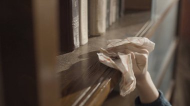 Kitaplığa toz silen bir çocuğun eline yakın çekim. Çocuk rafı temizliyor. Çocuğun eli kitaplığı temizliyor. Tozu siliyorum. Çocuğun kitaplığı temizlediği ve tozları sildiği en iyi manzara..