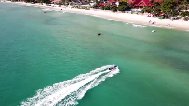 Aerial view of white sand beach and jet ski on the blue lagoon aqua sea. Aerial birds eye view of jet ski cruising in high speed in turquoise clear water sea — Stock Video