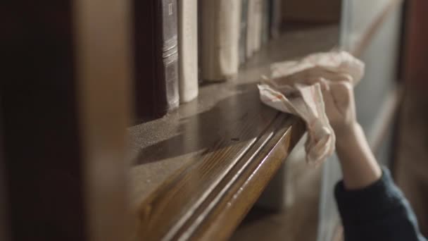 Close up van kinderen hand afvegen van een stof op de boekenplank. Kind opruimen van de plank. Jongens hand opruimen van de boekenkast. Vegen het stof. Bovenaanzicht van jongen schoonmaken van de boekenkast en vegen van stof — Stockvideo