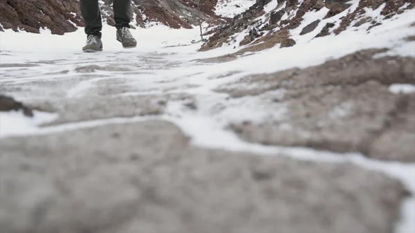 Nahaufnahme männlicher Beine in Winterschuhen, die auf Schnee laufen. Filmmaterial, Blick auf das Schneewandern mit Schneeschuhen und Schuhspikes im Winter. Männerbeine in Stiefeln versperren den verschneiten Weg — Stockfoto