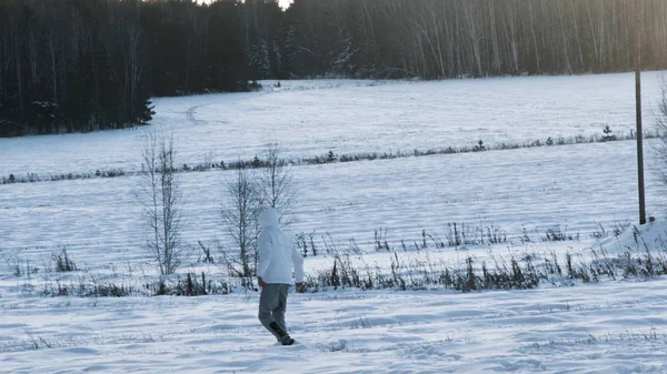 Una persona en un campo cubierto de nieve. Filmación. Vista trasera del hombre caminando en el campo nevado profundo. Hombre caminando en la nieve vista trasera —  Fotos de Stock
