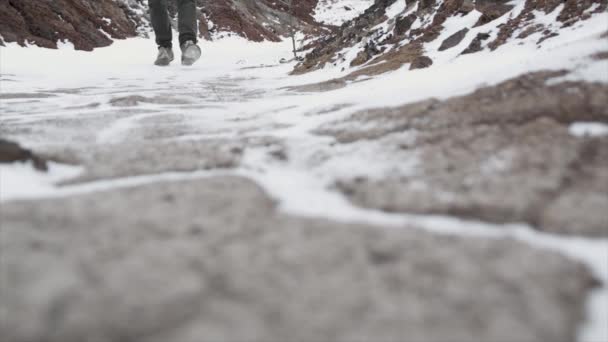 Primer plano de las piernas masculinas en zapatos de invierno caminando sobre la nieve. Filmación, Vista de caminar sobre la nieve con zapatos de nieve y picos de zapatos en invierno. Las piernas de los hombres en botas cierran el camino cubierto de nieve — Vídeos de Stock