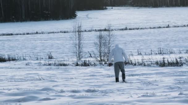 Een persoon op een besneeuwde veld. Beeldmateriaal. Achteraanzicht op Man lopen op diep besneeuwde veld. Man lopen in sneeuw achteraanzicht — Stockvideo