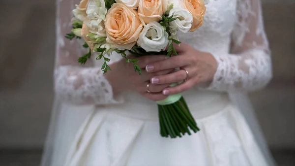 Nice wedding bouquet in brides hand. Clip. Fiancee in a beautiful white dress holding a beautiful bouquet of wedding flowers made of tender roses in hand — Stock Photo, Image