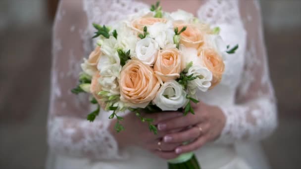 Joli bouquet de mariage dans la main des mariées. Clip. Fiancée dans une belle robe blanche tenant un beau bouquet de fleurs de mariage en roses tendres à la main — Video