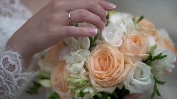 Fina brudbukett i brudar hand. Klipp. Fästmö i en vacker vit klänning som håller en vacker bukett av bröllop blommor gjorda av anbud rosor i handen — Stockvideo