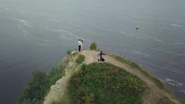 Casal em pé contra a vista incrível da natureza. Clipe. O casal está em pé num penhasco junto ao lago. Mundo da beleza. O sentimento de total liberdade. Aviação — Vídeo de Stock