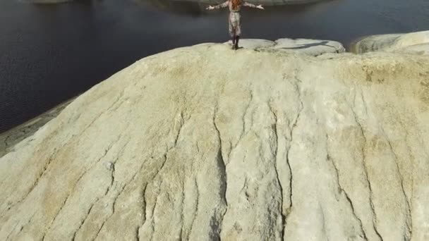 Kvinna med henne händerna upp stående på toppen av berget och sjön bakgrund. Footage. Kvinnlig turist andas fri luft på bergen. Smal flicka stående på toppen av kullen visar seger tecken. — Stockvideo