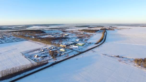 田舎の冬の風景。空撮。冬の小さな村の空撮。夕暮れ時の冬の雪に覆われた田舎の空撮。雪と森林に覆われ — ストック動画