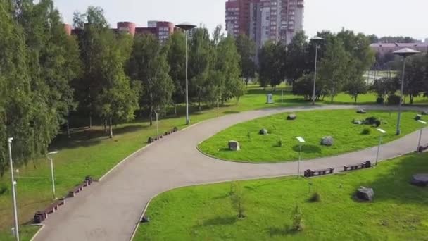 Weg in de buurt van het groene park, bovenaanzicht. Green Park en haar grote gazons op een zonnige lentedag. Clip. Luchtfoto van het gedreun van een stadspark met wandelen pad en groene zone bomen vliegen. Fietser in het Park — Stockvideo