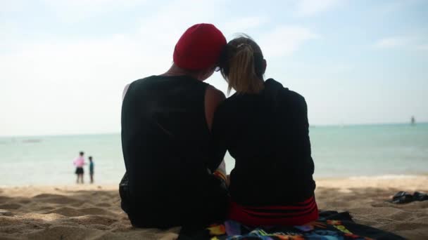 Kilka kochanek rozmieszczenie oglądać zachód słońca na plaży. Wideo. Szczęśliwa para kochać na tropikalnej plaży z widokiem na wyspy Similan. Młoda para romantyczny siedzący na plaży i przytulanie. — Wideo stockowe