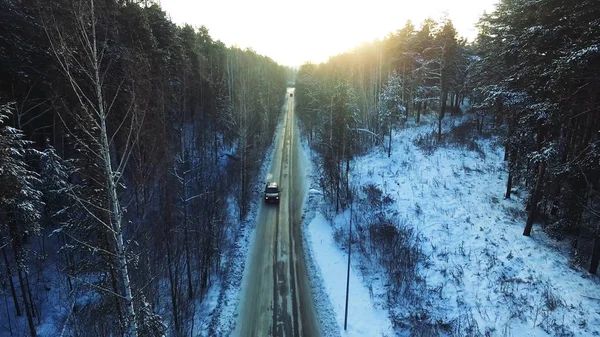 森の中で乗る車の平面図です。映像。森の中の冬道に行く車 — ストック写真