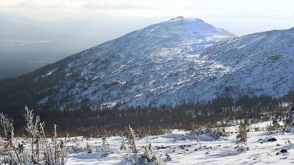 Winter mountain range scene, sun clouds and shadows over the snowy landscape. Video. Snowy mountains and sun shining. Mountain side and ridge covered in fresh powder snow