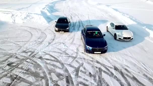 Rusia, Moscú - 12 de enero de 2018: Tres coches conducen por pista helada en el lago cubierto de nieve en invierno. Vista aérea. Carreras de coches deportivos en pista de carreras de nieve en invierno. Conducir un coche de carreras en una carretera nevada . — Vídeos de Stock