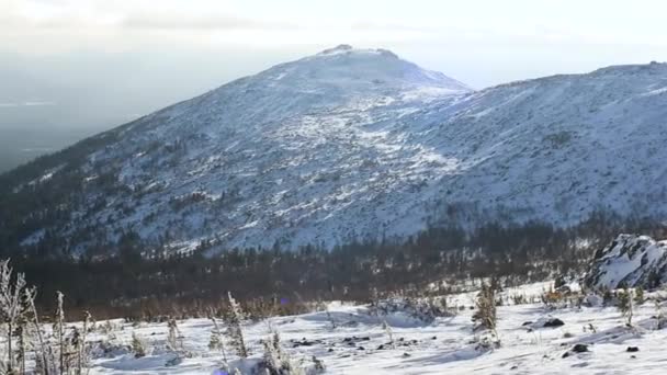 Escena montañosa invernal, nubes de sol y sombras sobre el paisaje nevado. Vídeo. Montañas nevadas y sol brillando. Lado de la montaña y cresta cubierta de nieve fresca en polvo — Vídeo de stock