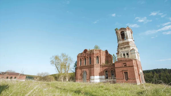 Ruinas de una iglesia abandonada de ladrillos rojos en Rusia. Vídeo. Al aire libre en el campo sobre fondo azul cielo de verano. Hermosa vista panorámica del antiguo templo budista en el fondo del campo . —  Fotos de Stock