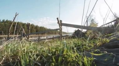 Ahşap çit ve güneş yansıma yeşil çim ve göl mavi gökyüzü arka plan ile. Video. Kırsal önde gelen bir çiftlik kapısı görünümünü. Kırsal manzara