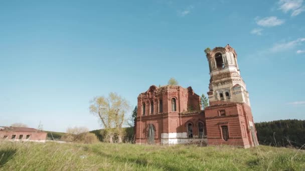 Ruinas de una iglesia abandonada de ladrillos rojos en Rusia. Vídeo. Al aire libre en el campo sobre fondo azul cielo de verano. Hermosa vista panorámica del antiguo templo budista en el fondo del campo . — Vídeo de stock