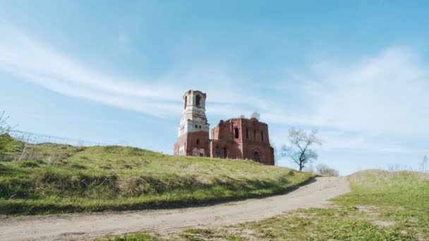 Ruiny jednego opuszczony Kościół z czerwonej cegły, w Rosji. Wideo. Odkryty na pole na lato niebieski niebo tła. Piękne widoki starożytnej świątyni buddyjskiej w tle pola. — Wideo stockowe