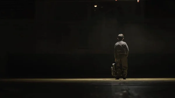 Мальчик с рюкзаком в спортзале. Мальчик идет на тренировку по дзюдо в темноте выходит на свет — стоковое фото