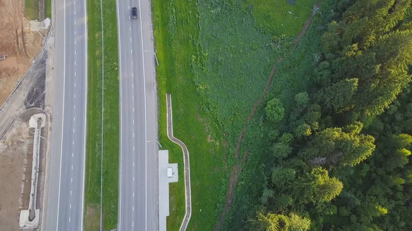 Vue aérienne de la route de campagne passant près de la forêt dans les forêts à feuilles persistantes du nord. Clip. Vue de dessus de l'autoroute près de la forêt — Photo