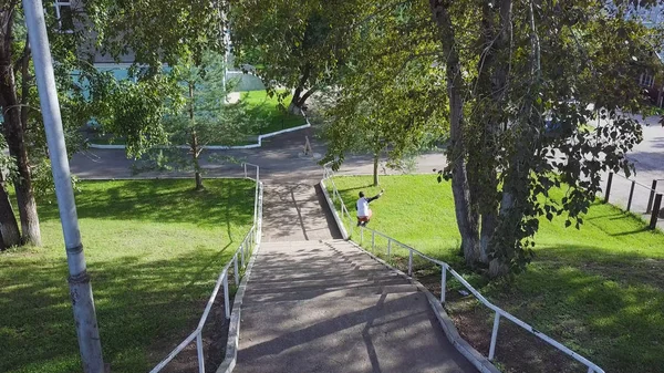 Agressieve inline roller blader grind op rail in skatepark buiten. Clip. Zomer extreme sport uitoefenen buiten in het Skatepark. Skater jongen slijpen op leuning in park. Cool activiteit hobby voor jong — Stockfoto