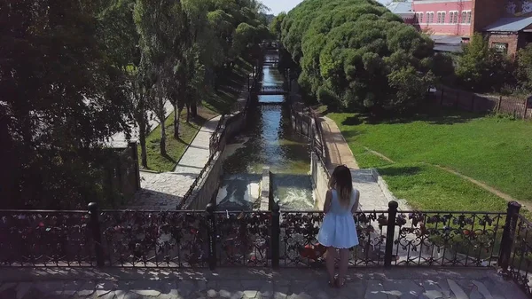 Joven turista disfrutando de una hermosa vista del paisaje en el casco antiguo. Clip. Vista superior de la chica de pie en el puente — Foto de Stock