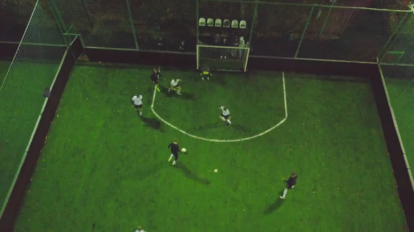 Pemandangan udara lapangan sepak bola di malam hari dengan pemain sepak bola amatir bermain permainan di kota. Jepit. Pemandangan terbaik dari para pemain di lapangan — Stok Foto
