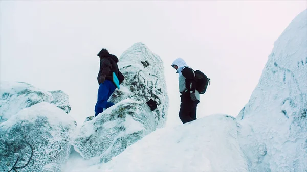 Giovani uomini arrampicata su vetta innevata. Un video. Due scalatori in piedi sulla cima sopra le nuvole in montagna. Due scalatori seduti sulla cima della montagna — Foto Stock