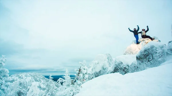 Unga män bergsklättring på snöiga topp. Video. Två klättrare stående ovanpå toppmötet ovan molnen i bergen. Två klättrare som sitter på toppen av berget — Stockfoto