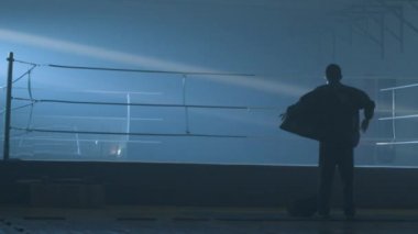 Genç sportif erkek boxer düzenli boks halka bir spor salonunda yakın duran silüeti. Arkadan görünüş adam boks halka yakın Tarih