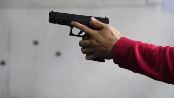 Gun in the mans hand. Man holding a gun close-up. Black handgun in hand of a man