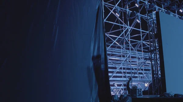 Silhouette of a man repairing concert equipment. The stage worker sets up the lights.