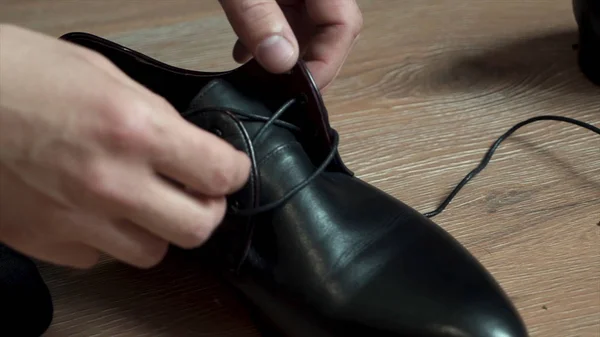 Hombre de negocios atando cordones de zapatos en el suelo. Primer plano. Un hombre lleva zapatos negros en primer plano. Hombre de negocios atando cordones de zapatos en el suelo. Primer plano . — Foto de Stock