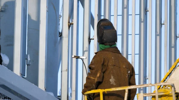 Welder ve výtahu. Stavební pracovník stojící na žebříku a svářečských ocelových trámech na staveništi. Welder na staveništi. — Stock fotografie