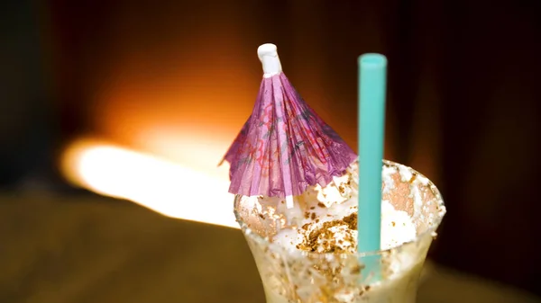 Um morango de milkshake com creme e palha de bebida. Branco agitar em vidro com guarda-chuva de perto — Fotografia de Stock