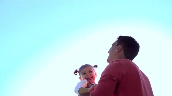 Отец играет со своей дочерью на фоне голубого неба и солнечного отражения. День Отцов. Счастливого счастливого отца, веселящегося, тошнит в воздушного ребенка. Счастливая девушка, брошенная в голубое небо своим отцом . — стоковое фото