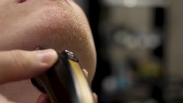 Портрет молодого бородатого человека, ухаживающего за бородой в современной парикмахерской в замедленной съемке. Парикмахер, обслуживающий клиента, делает стрижку бороды с помощью бритвы. Береги свою бороду. — стоковое видео