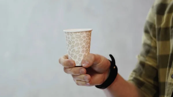 Un oficinista sostiene una taza de porcelana que se reemplaza con una taza de papel. El concepto de trabajo de oficina Imagen de archivo