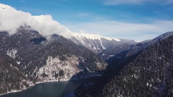 Panoramablick auf die wunderschöne weiße Winterlandschaft mit verschneiten Berggipfeln. Clip. Kristallklarer Bergsee an einem kalten, sonnigen Tag mit blauem Himmel und Wolken — Stockvideo