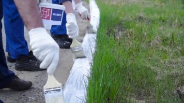 Beyaz eldiven giyen ve sınırında bir boya fırçası ile boyama el ile çalışan insanlar. Küçük. Çalışanlar formundaki boyalı