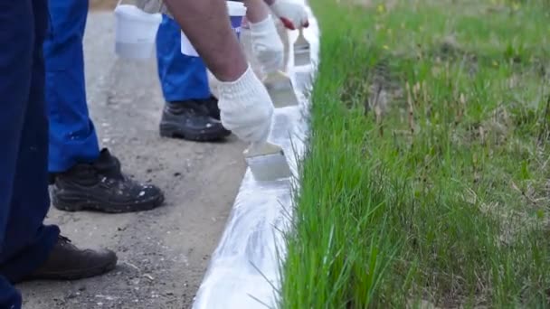 Pessoas que trabalham com Mão usando luvas brancas e pintura com um pincel de tinta nas bordas. Clipe. Trabalhadores em forma pintada — Vídeo de Stock