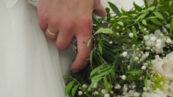 Schöner Brautstrauß in der Hand der Bräute. Clip. Verlobte in einem wunderschönen weißen Kleid mit einem wunderschönen Strauß Hochzeitsblumen aus zarten Rosen in der Hand — Stockvideo