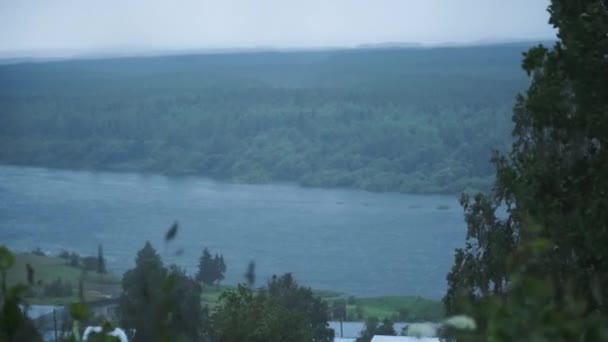 Bergsby på stranden av floden. Klipp. Utsikt över floden nära byn i molnigt väder och starka vindar — Stockvideo