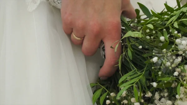 Гарний весільний букет в руці наречених. Кліп. Фітнес в красивій білій сукні тримає красивий букет весільних квітів з ніжних троянд в руці — стокове фото
