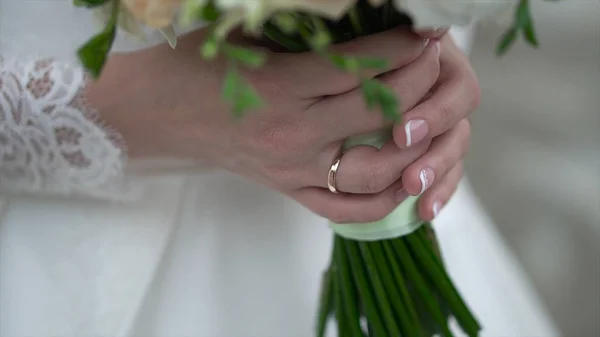 Nice wedding bouquet in brides hand. Clip. Fiancee in a beautiful white dress holding a beautiful bouquet of wedding flowers made of tender roses in hand — Stock Photo, Image