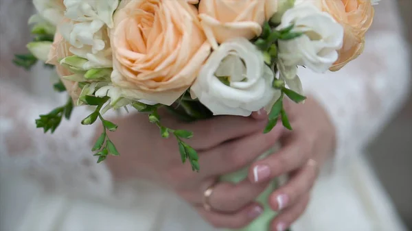 Хороший свадебный букет в руке невесты. Клип. Невеста в красивом белом платье с красивым букетом свадебных цветов из нежных роз в руке — стоковое фото