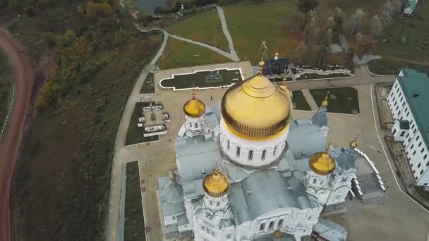 Вид сверху на большой христианский искушение. Клип. Вид на церковь снаружи. Старая церковь. Каменная церковь с золотыми куполоми осенью — стоковое видео